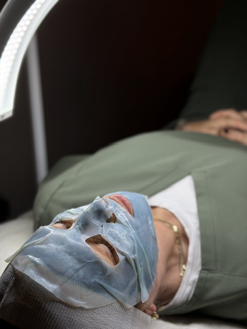 female on bed with mask during facial